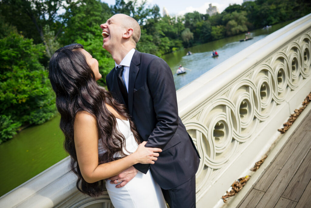 Bride and groom laughing on Central Park's Bow Bridge