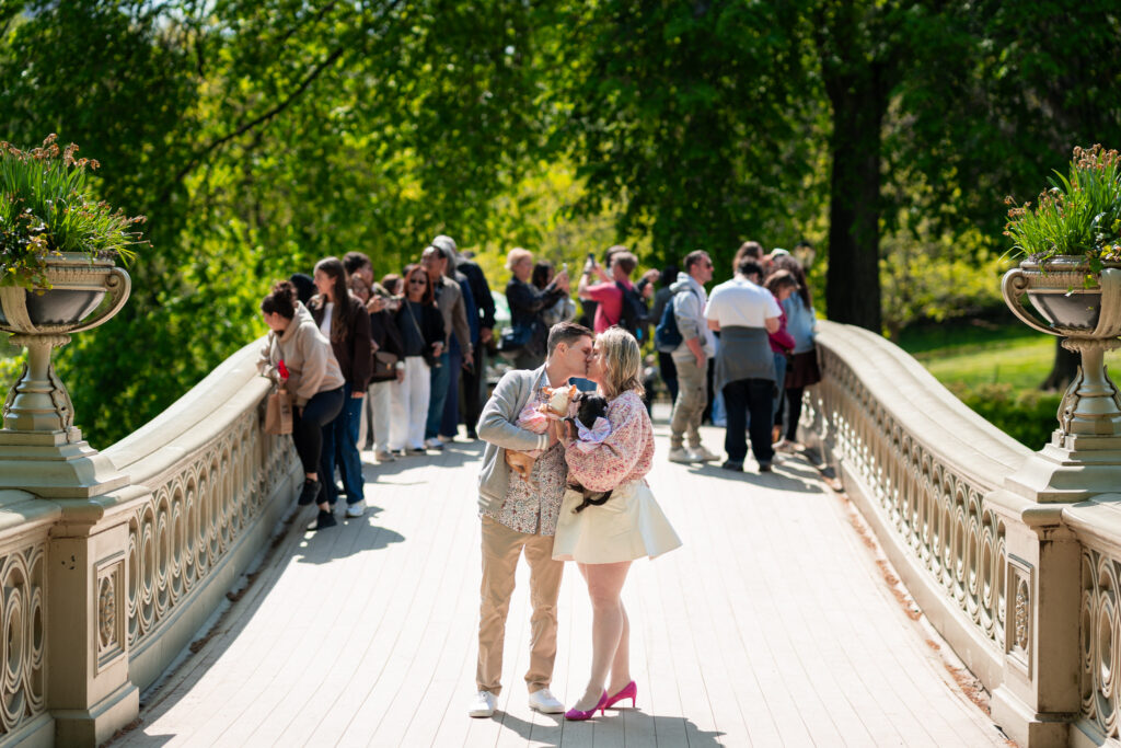 Engaged couple kissing on Bow Bridge in Central Park